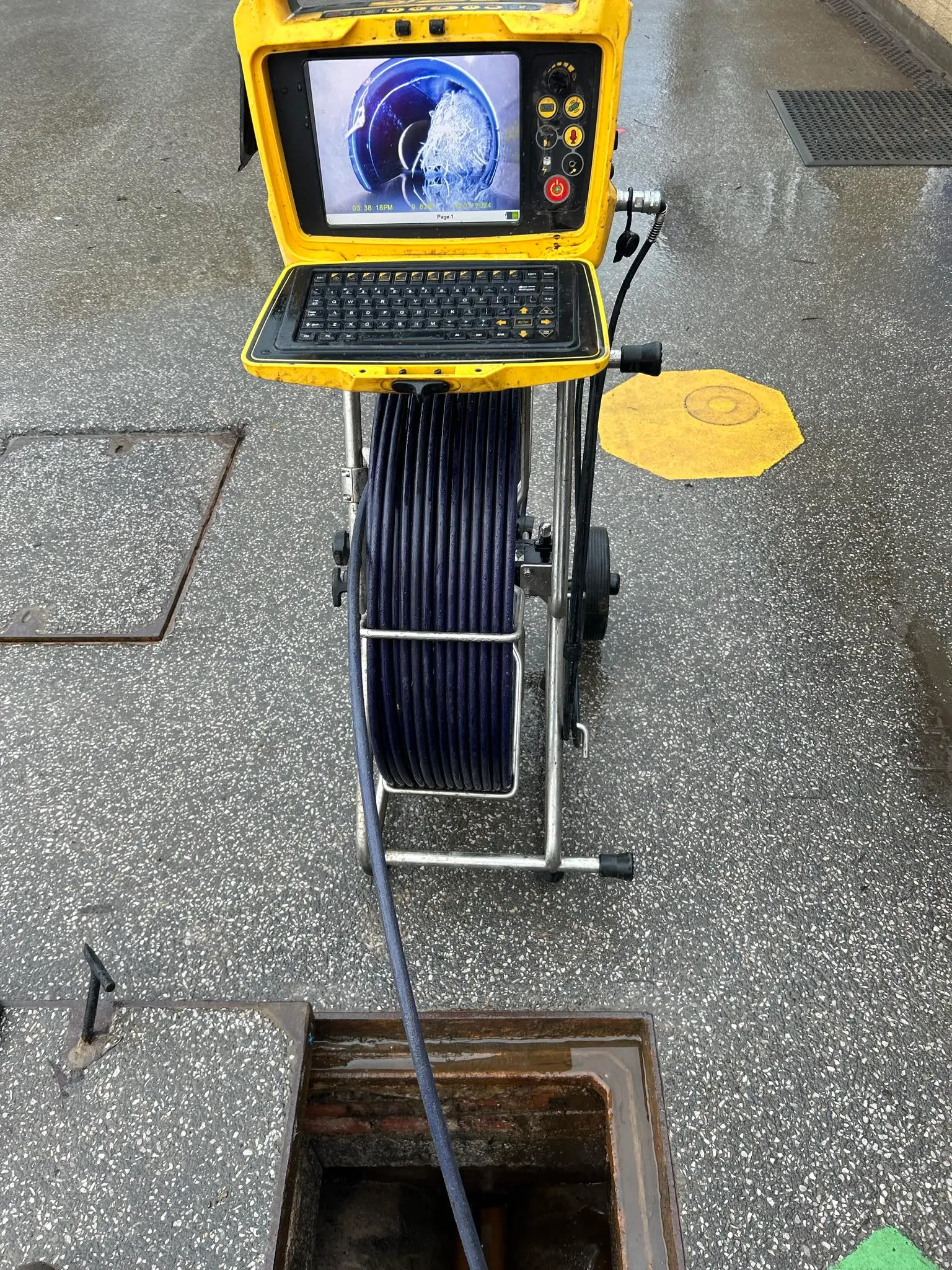 A CCTV drain survey camera and monitor showing the inside of a pipe with a blockage.
